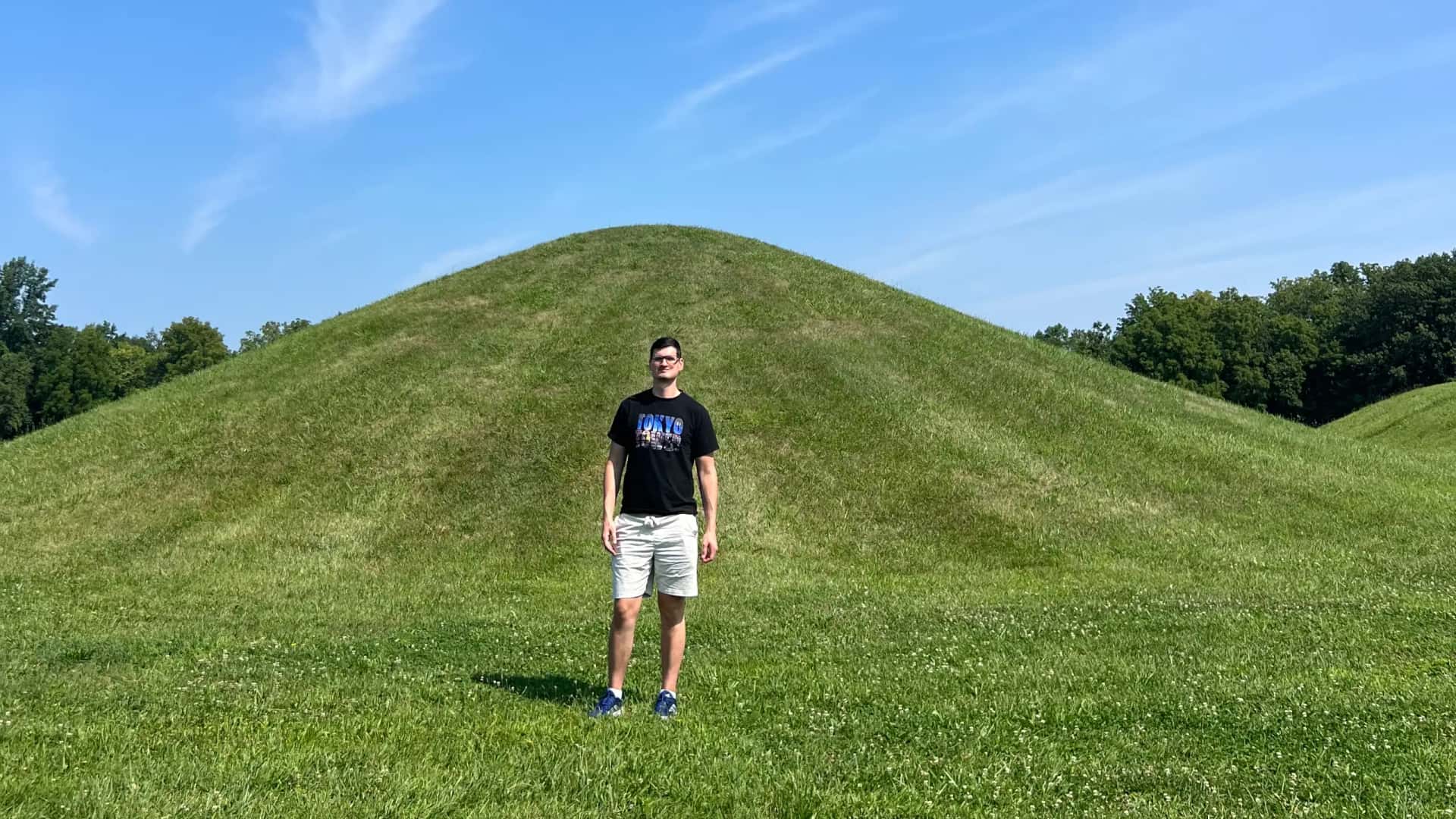 A traveler standing in front of an ancient, grass-covered earthwork at the Mound City Group in Hopewell Culture National Historical Park, a UNESCO World Heritage Site in Chillicothe, Ohio.