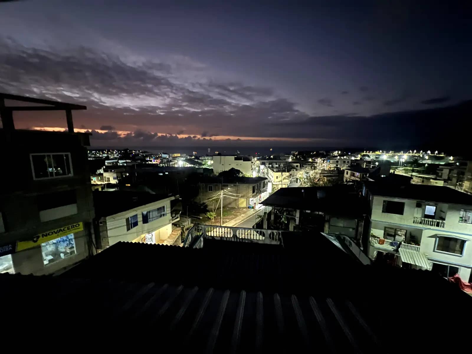 Twilight view of San Cristobal Island town rooftops and ocean horizon from balcony at La Casa de Celeste hotel Galapagos Islands Ecuador