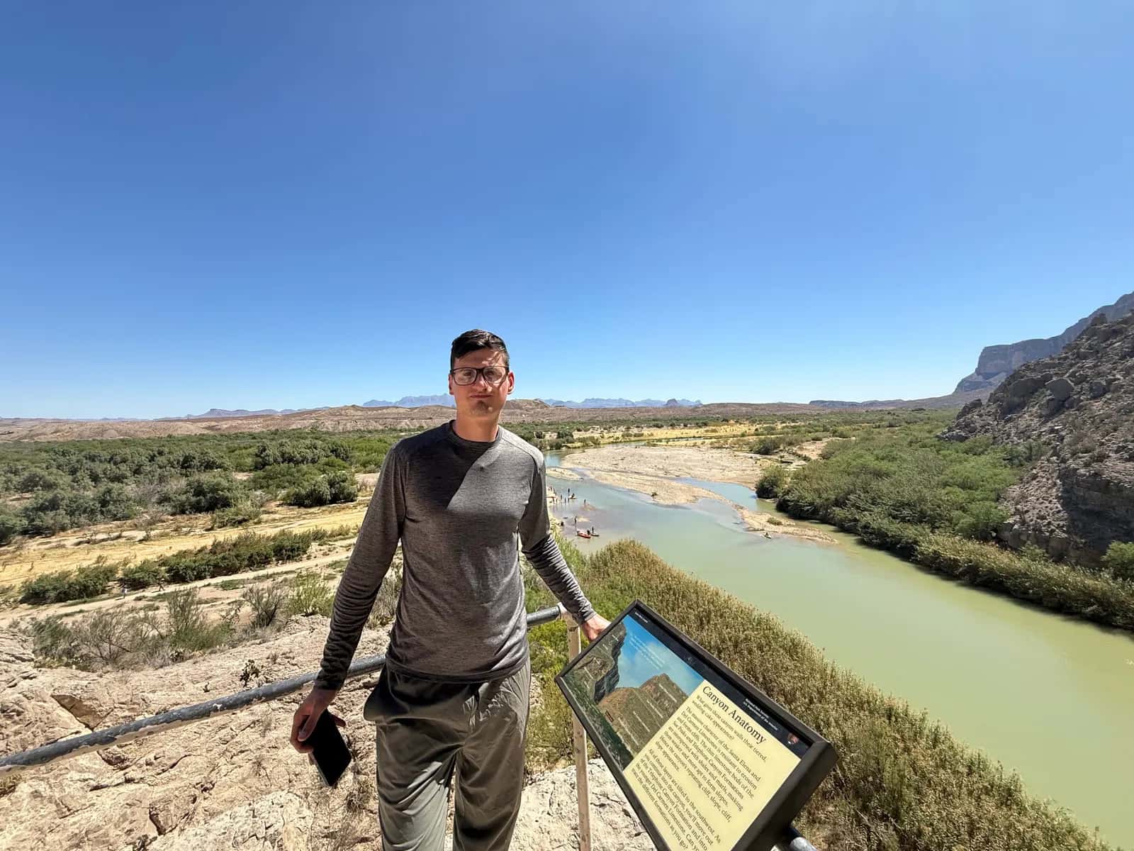 Blog header showing a man in glasses standing before a wide desert river valley under a clear blue sky.