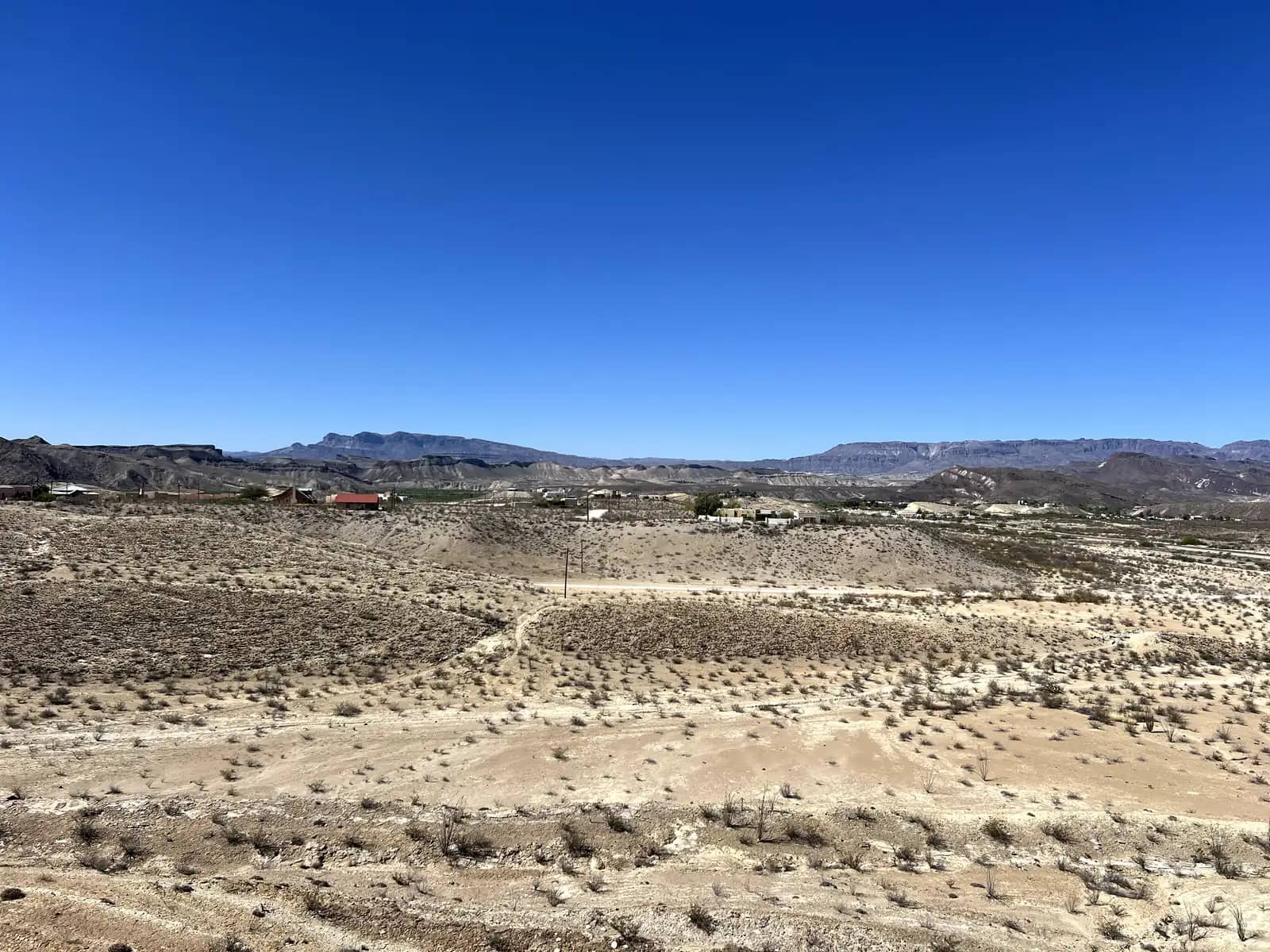 A vast, brushy West Texas desert landscape vista with a deep, dry arroyo winding into the distance.
